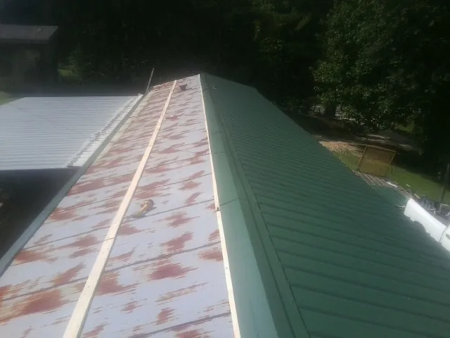 Old rusted panels beside newly installed green metal roofing — Wind Damage Roof Repair by Roofing Brothers in High Shoals