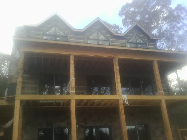 Dormers and porch framing on a large log home under construction — Roof Coating work by our crew in High Shoals