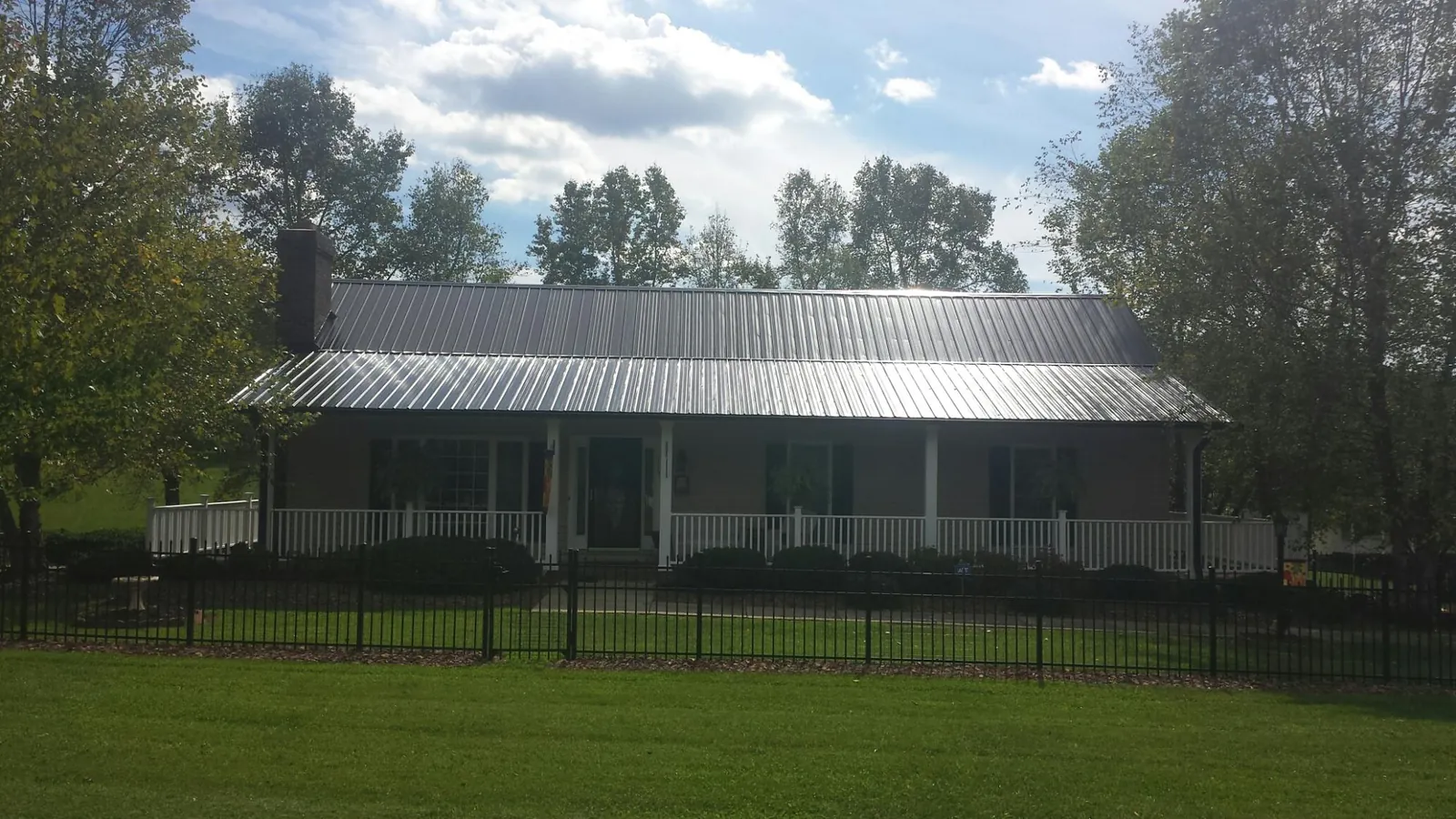 Gray metal roof on a brick ranch with a full width front porch — Gutter Guard Installation work by our crew in High Shoals