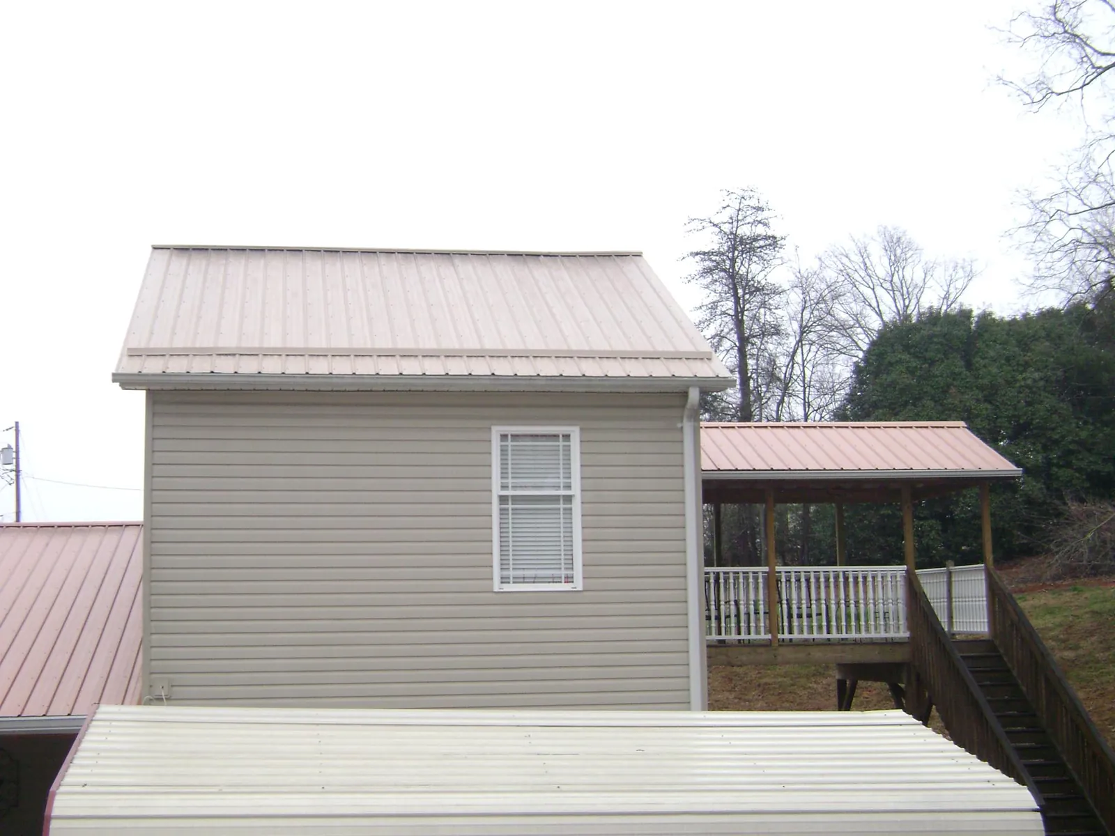 Tan metal roofs on a two story addition and attached porch, from a Roof Replacement job in High Shoals