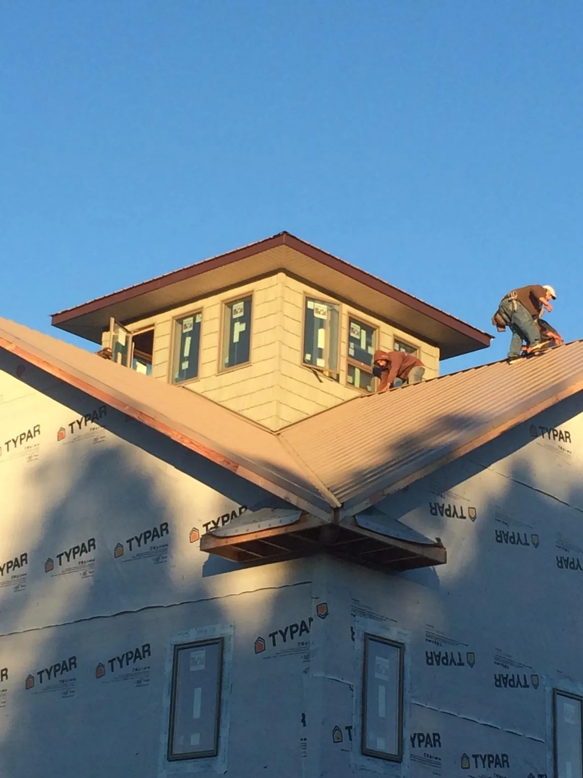 Roofers working around a rooftop cupola on a new metal roof at sunset — Roof Waterproofing in High Shoals by Roofing Brothers